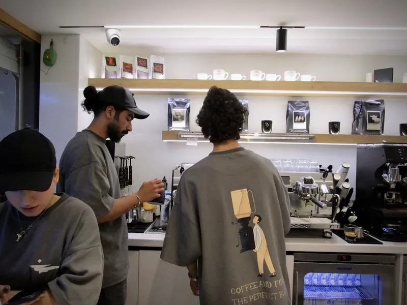Baristé připravují kávu za pultem kavárny