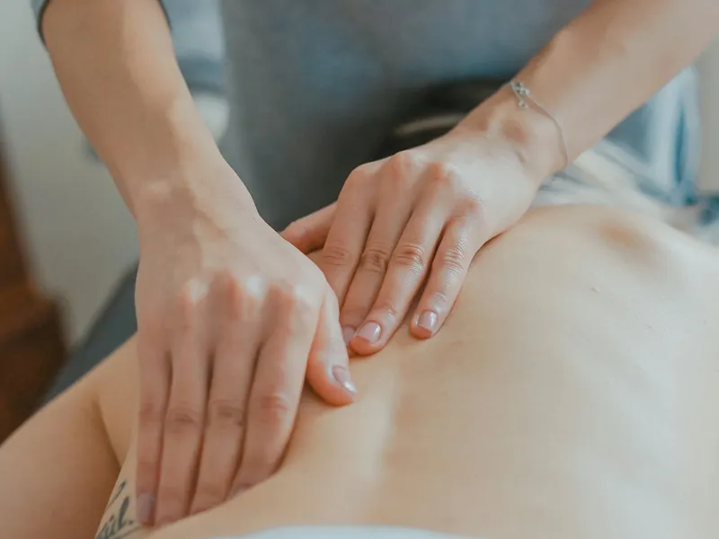 Masérka provádí masáž zad na masážním lehátku